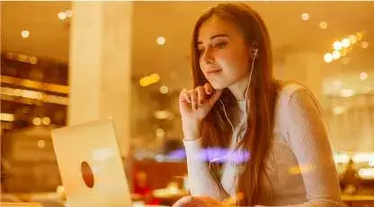 Una mujer joven escucha música y navega en su portatil con el Plan Novice Defense para trabajar